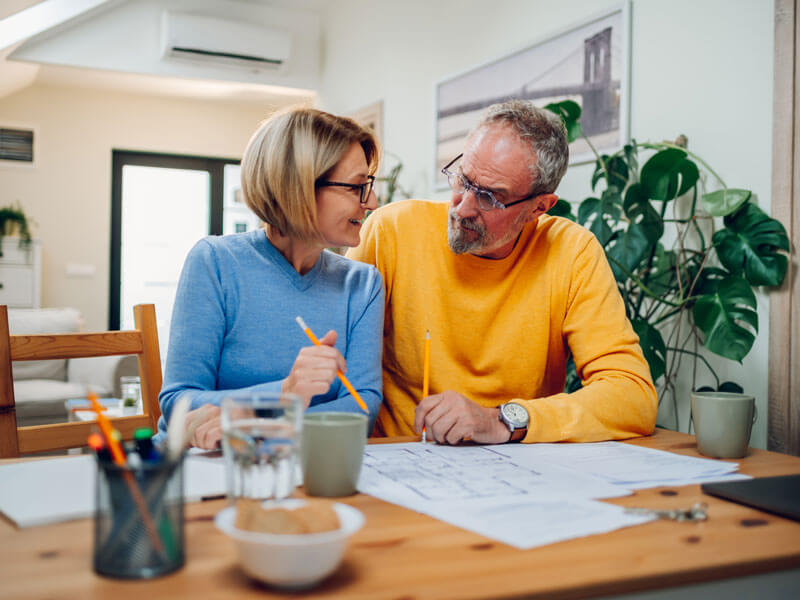 Senior couple sitting at table and discussing home renovation plans